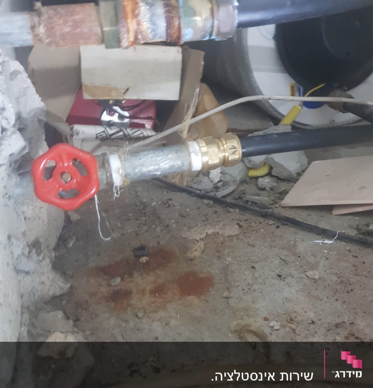 שסתום אדום מחובר לצינור מתכת על רצפה